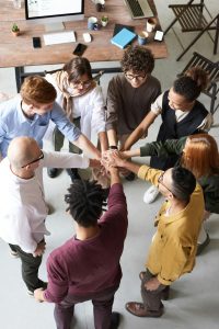 Eight people all standing in a circle and joining hands in the middle